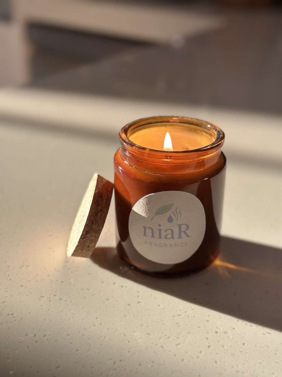 niaR 香氛蠟燭實拍：自然光下點燃的棕色玻璃燭瓶